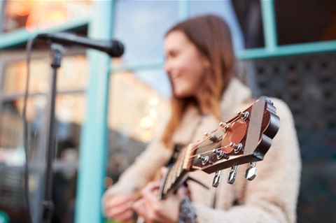 A woman with a guitar busking.