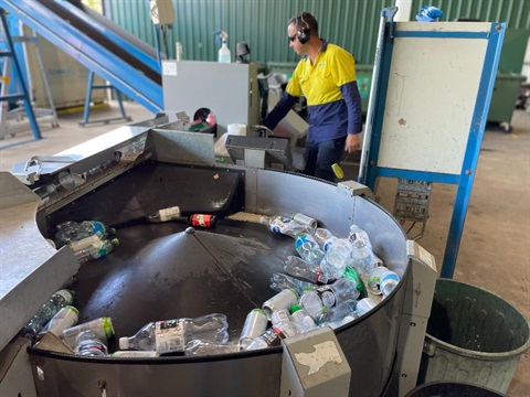 A Council staff worker operates the Return & Earn machine.