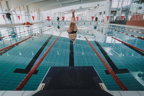 A man dives off the blocks into a lap lane in a swimming pool.