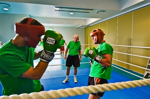 Two men box in a ring with an umpire watching.