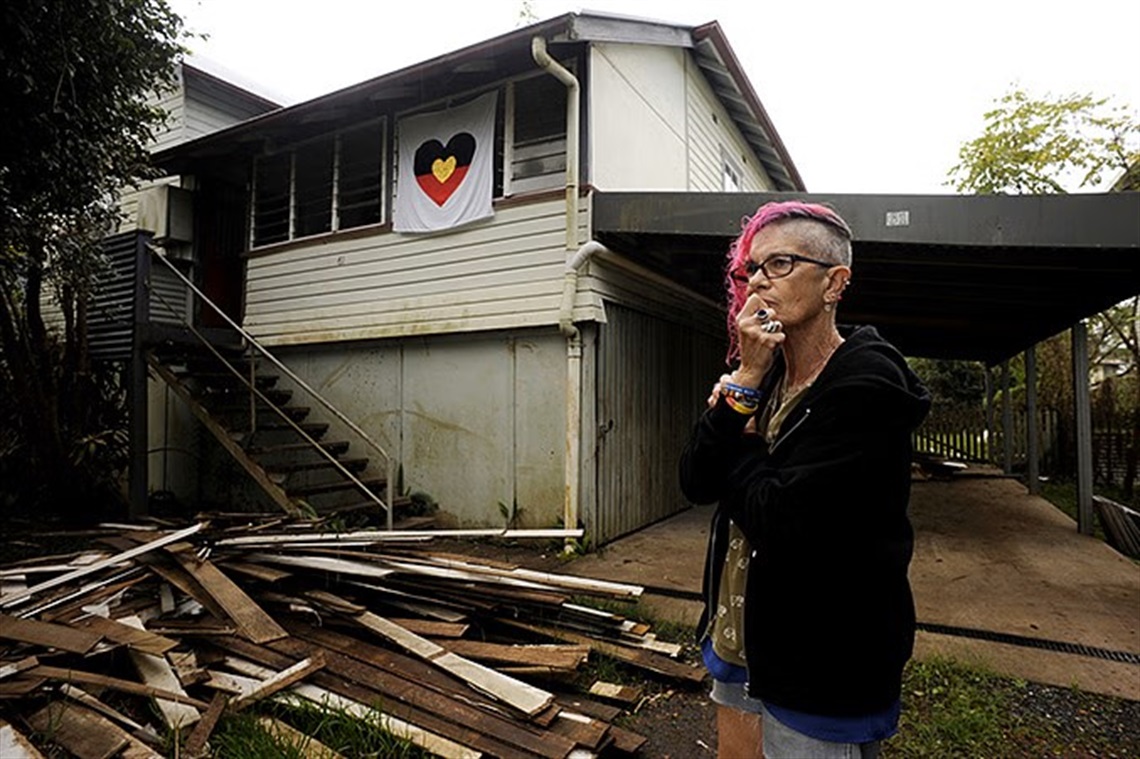 Kerry Andersen stands in front of her flood-damaged home.