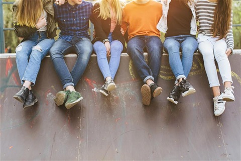 a group of young friends stand against a wall.
