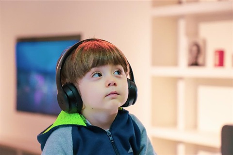 A young boy sits with headphones over his ears.
