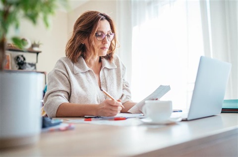 A woman sits at her laptop.