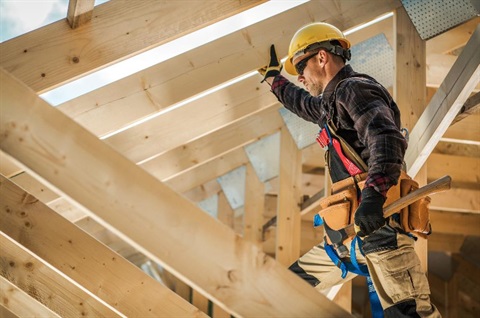 A builder standing amongst a house being built.
