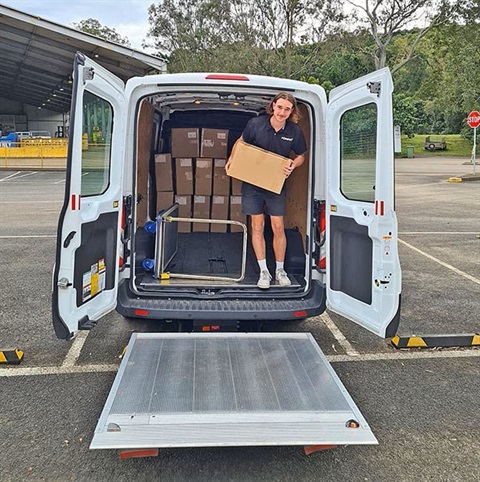 A man unloads boxes from the back of a van.