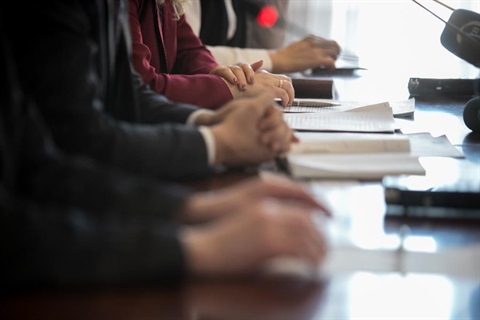 People sitting at a long desk in a meeting.