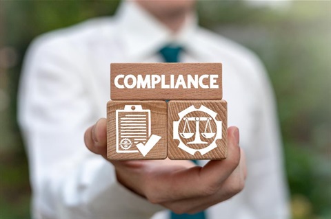 A man holding wooden blocks with the word compliance on them.