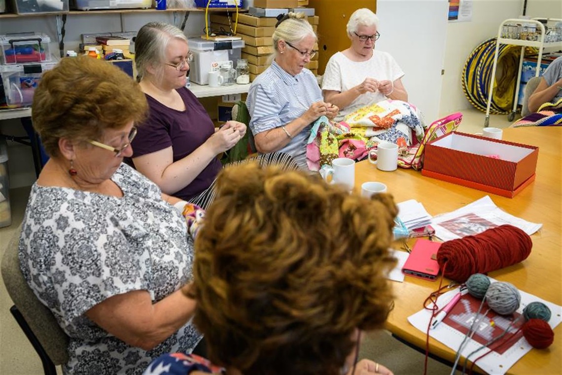 group of ladies sitting together doing various crafts