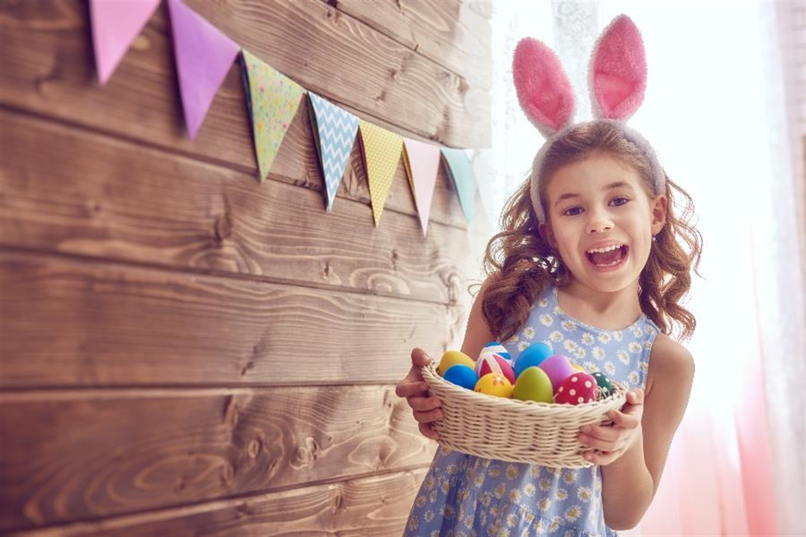 A girl holding a basket of Easter eggs.