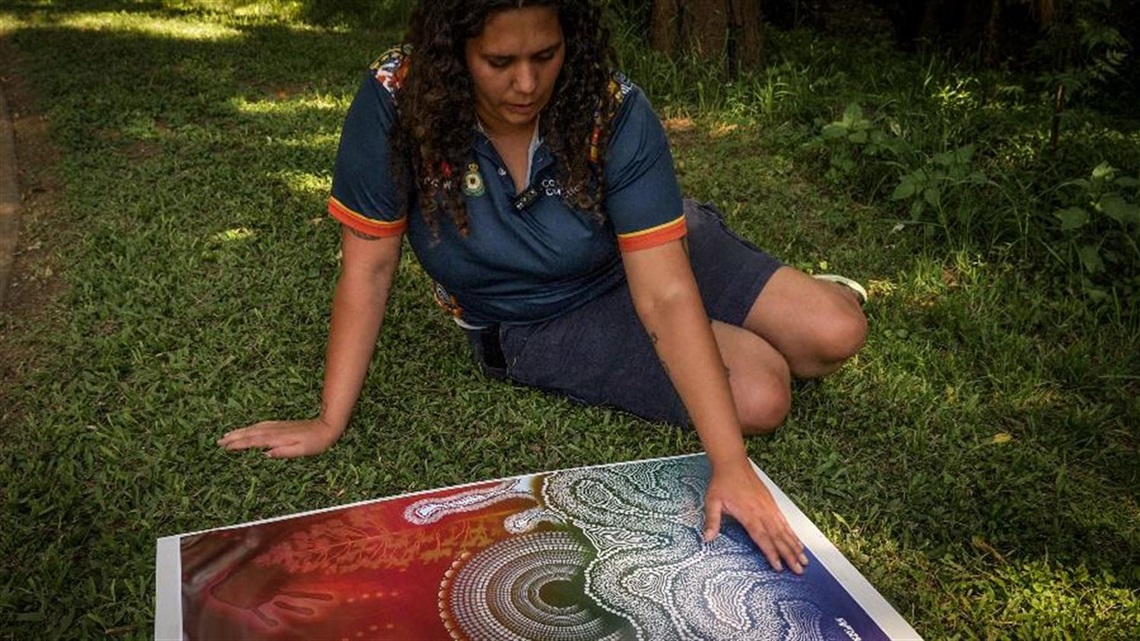 Artist Tywana Caldwell looking at her artwork
